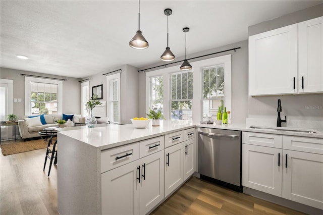 1010 E Lake Ave, Tampa, FL 33605 - kitchen featuring stainless steel dishwasher, a sink, wood finished floors, light countertops, and white cabinetry