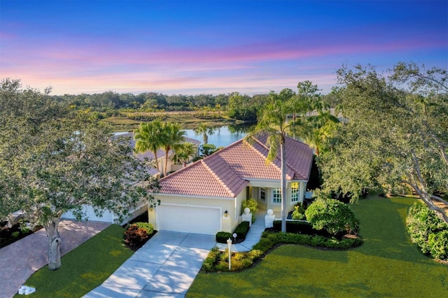 view of front of house featuring a water view, a garage, and a lawn