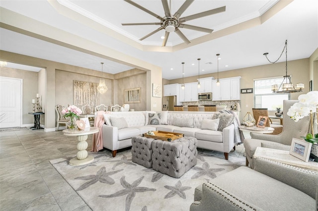 living room featuring ornamental molding, a tray ceiling, and ceiling fan with notable chandelier