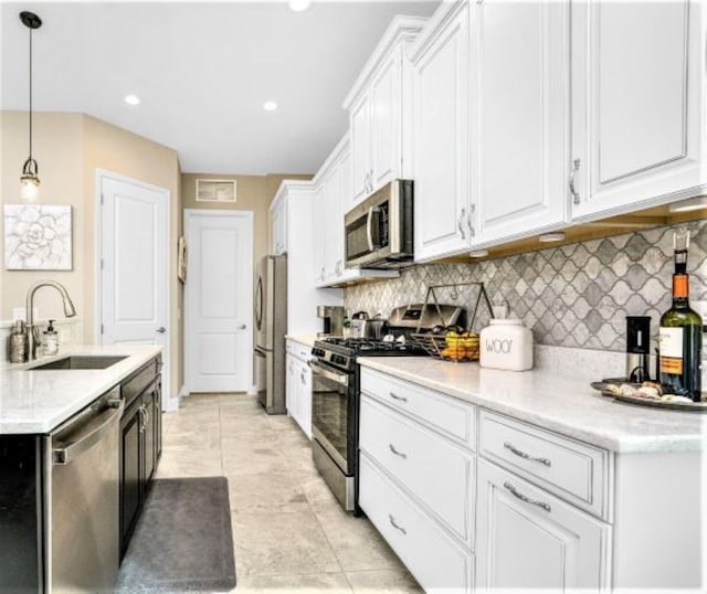 kitchen with sink, appliances with stainless steel finishes, hanging light fixtures, tasteful backsplash, and white cabinets