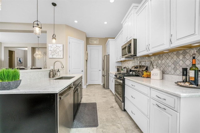 kitchen with hanging light fixtures, stainless steel appliances, light stone countertops, decorative backsplash, and white cabinets