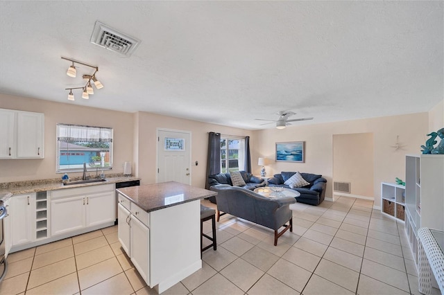 kitchen featuring light tile patterned flooring, a center island, sink, and white cabinets