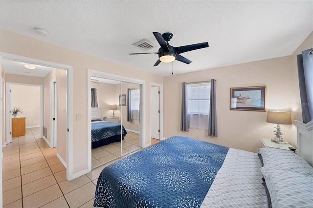 tiled bedroom with ceiling fan, a closet, and a textured ceiling