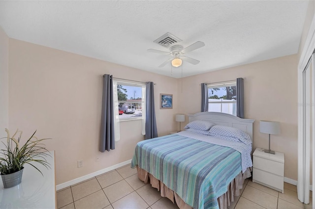 bedroom with ceiling fan, light tile patterned floors, and a textured ceiling