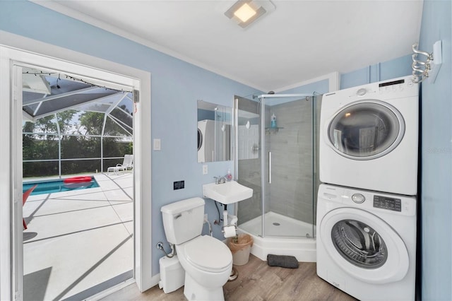 laundry area with sink, hardwood / wood-style flooring, and stacked washing maching and dryer