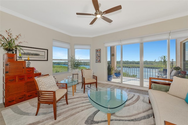 living area featuring a water view, ceiling fan, ornamental molding, and light wood-type flooring