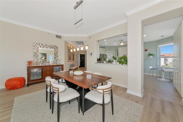 dining space featuring crown molding and light hardwood / wood-style flooring