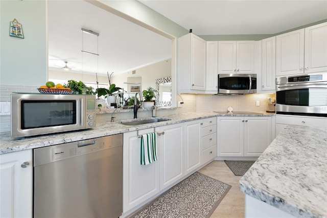 kitchen with stainless steel appliances, white cabinetry, sink, and backsplash