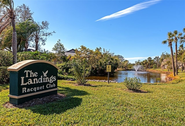 community sign featuring a water view and a lawn