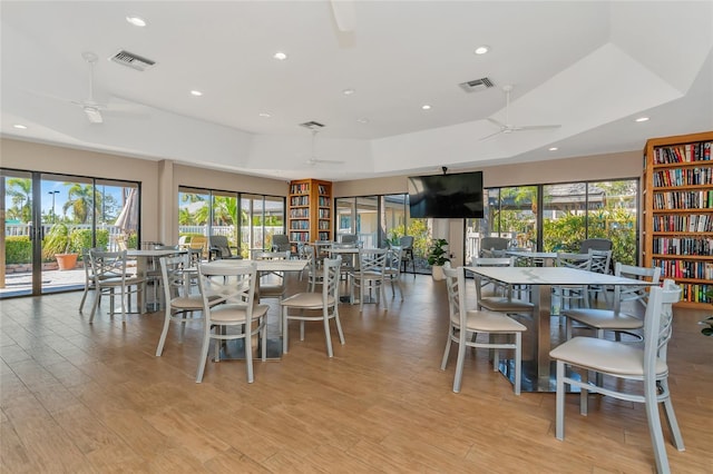 dining room featuring a tray ceiling, ceiling fan, and light hardwood / wood-style floors