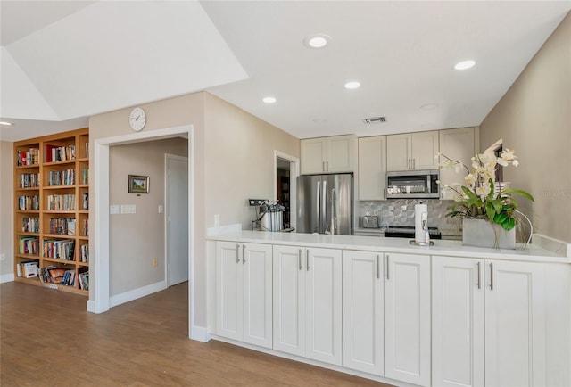 kitchen with decorative backsplash, stainless steel appliances, and light hardwood / wood-style floors