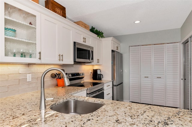 kitchen featuring tasteful backsplash, light stone countertops, stainless steel appliances, and white cabinets