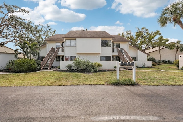 view of front of property with a balcony and a front lawn