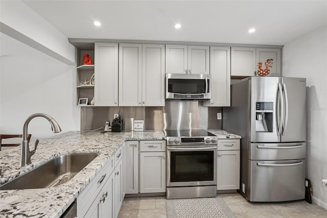 kitchen featuring gray cabinetry, sink, light stone countertops, and appliances with stainless steel finishes