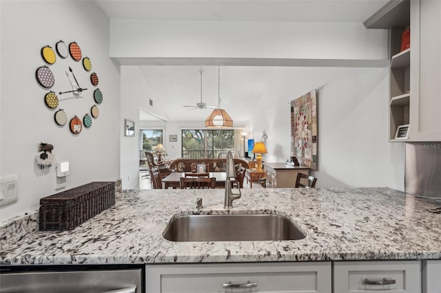 kitchen featuring light stone counters, stainless steel dishwasher, and sink