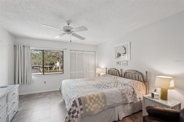 tiled bedroom with a textured ceiling, ceiling fan, and a closet