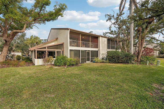 rear view of property with a sunroom and a lawn