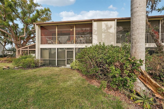 back of property with a yard and a sunroom