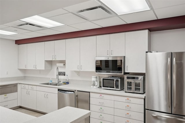 kitchen with stainless steel appliances, sink, a paneled ceiling, and white cabinets