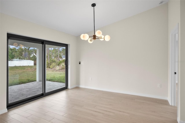 empty room featuring an inviting chandelier, vaulted ceiling, and light hardwood / wood-style floors