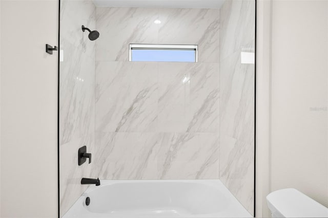 bathroom featuring tiled shower / bath and toilet