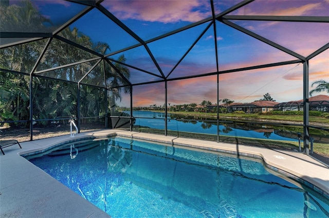 pool at dusk featuring a lanai, a patio, and a water view