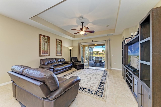 tiled living room featuring a raised ceiling and ceiling fan