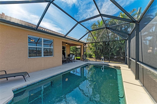 view of swimming pool with a patio, ceiling fan, and glass enclosure