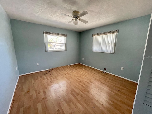 empty room with ceiling fan, a textured ceiling, and light wood-type flooring