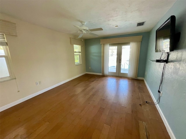 empty room with french doors, ceiling fan, wood-type flooring, and a textured ceiling