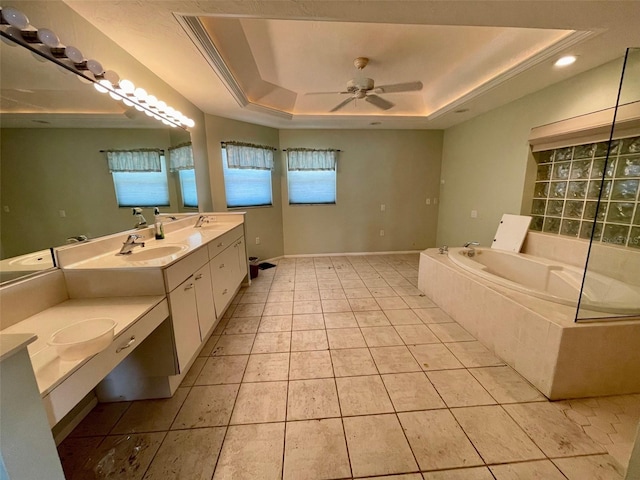 bathroom featuring vanity, a tray ceiling, a relaxing tiled tub, ceiling fan, and tile patterned flooring