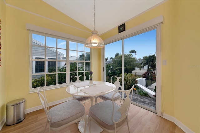 dining area featuring vaulted ceiling, a healthy amount of sunlight, and light hardwood / wood-style flooring