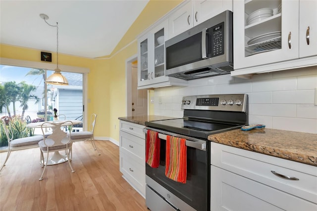 kitchen with tasteful backsplash, appliances with stainless steel finishes, dark stone countertops, and white cabinets