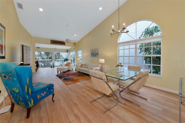 dining space with a notable chandelier, a towering ceiling, and light wood-type flooring