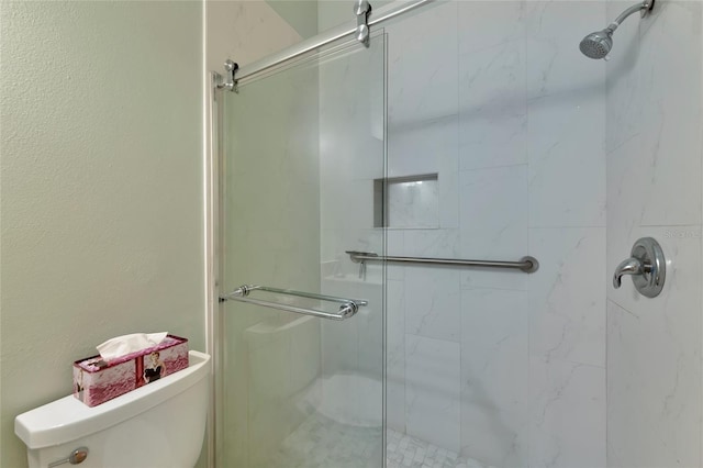 bathroom featuring toilet and a shower with shower door