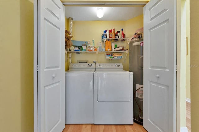 clothes washing area featuring washing machine and clothes dryer and light wood-type flooring