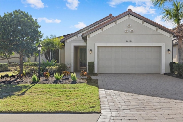 ranch-style house with a garage, a front yard, decorative driveway, and stucco siding