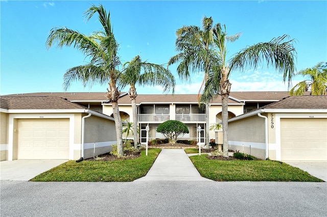 view of front facade featuring a front lawn, a garage, and a sunroom