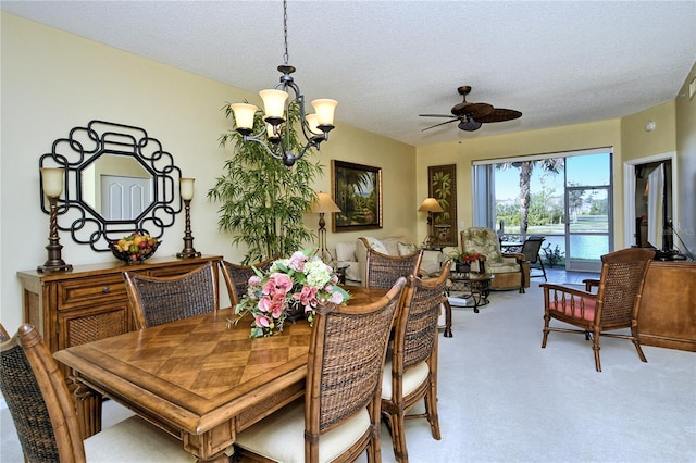 carpeted dining space featuring ceiling fan with notable chandelier and a textured ceiling