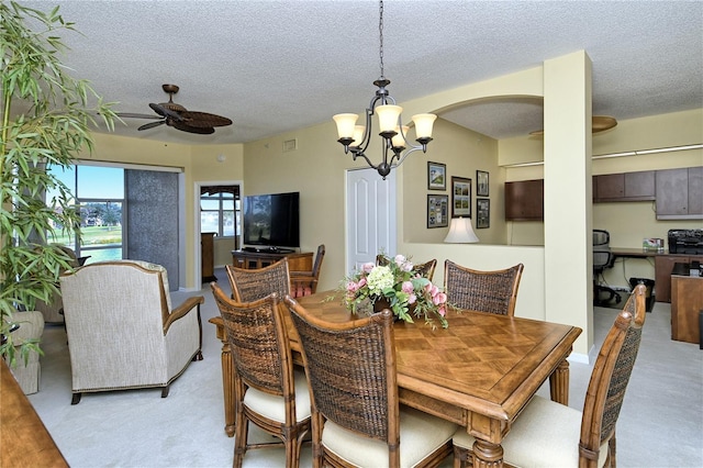 dining room featuring ceiling fan with notable chandelier, light colored carpet, and a textured ceiling