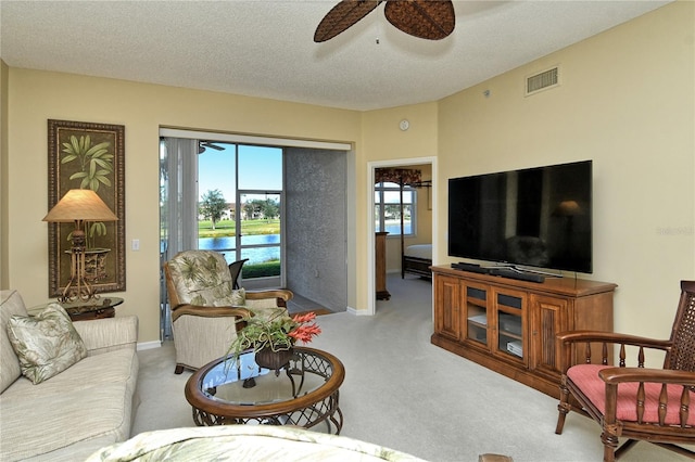 carpeted living room with ceiling fan and a textured ceiling