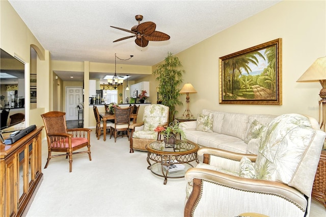 carpeted living room featuring ceiling fan with notable chandelier and a textured ceiling