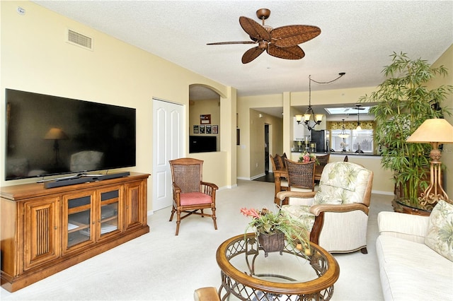 carpeted living room featuring ceiling fan with notable chandelier and a textured ceiling