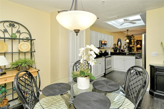 dining room with ceiling fan, dark hardwood / wood-style floors, a skylight, and sink