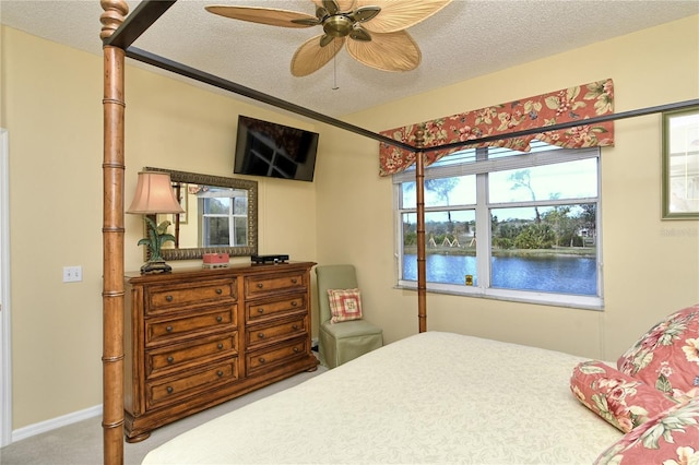 carpeted bedroom featuring ceiling fan and a textured ceiling