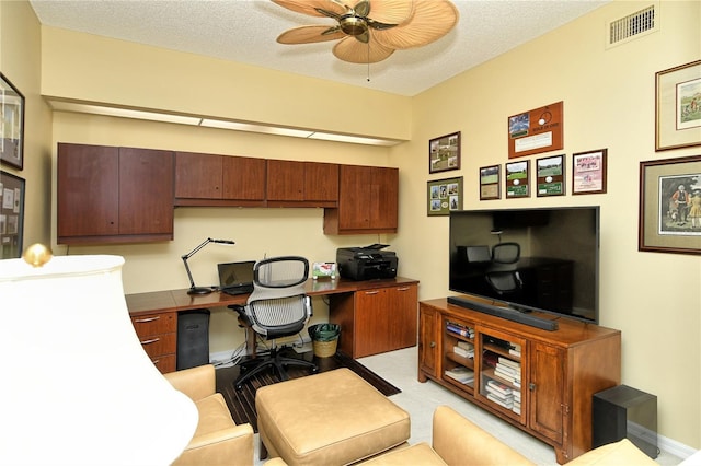 office featuring ceiling fan, built in desk, and a textured ceiling