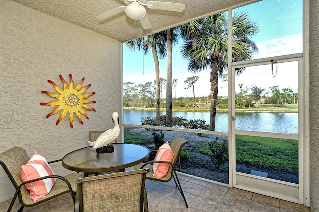 sunroom / solarium featuring a water view and ceiling fan