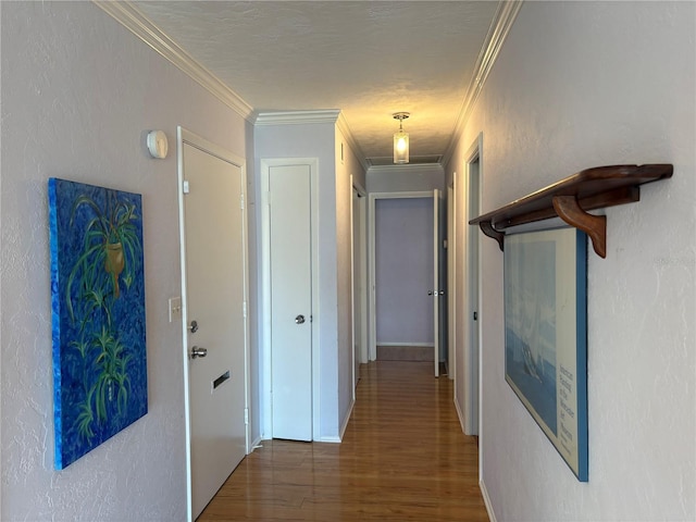 hall featuring ornamental molding, dark wood-type flooring, and a textured ceiling