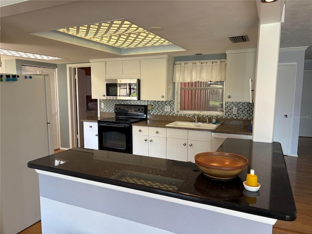 kitchen featuring sink, hardwood / wood-style flooring, appliances with stainless steel finishes, backsplash, and white cabinets