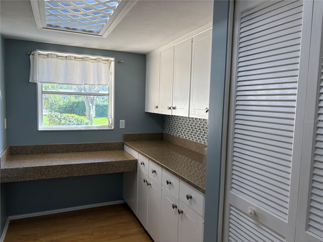 kitchen with wood-type flooring, white cabinets, and decorative backsplash